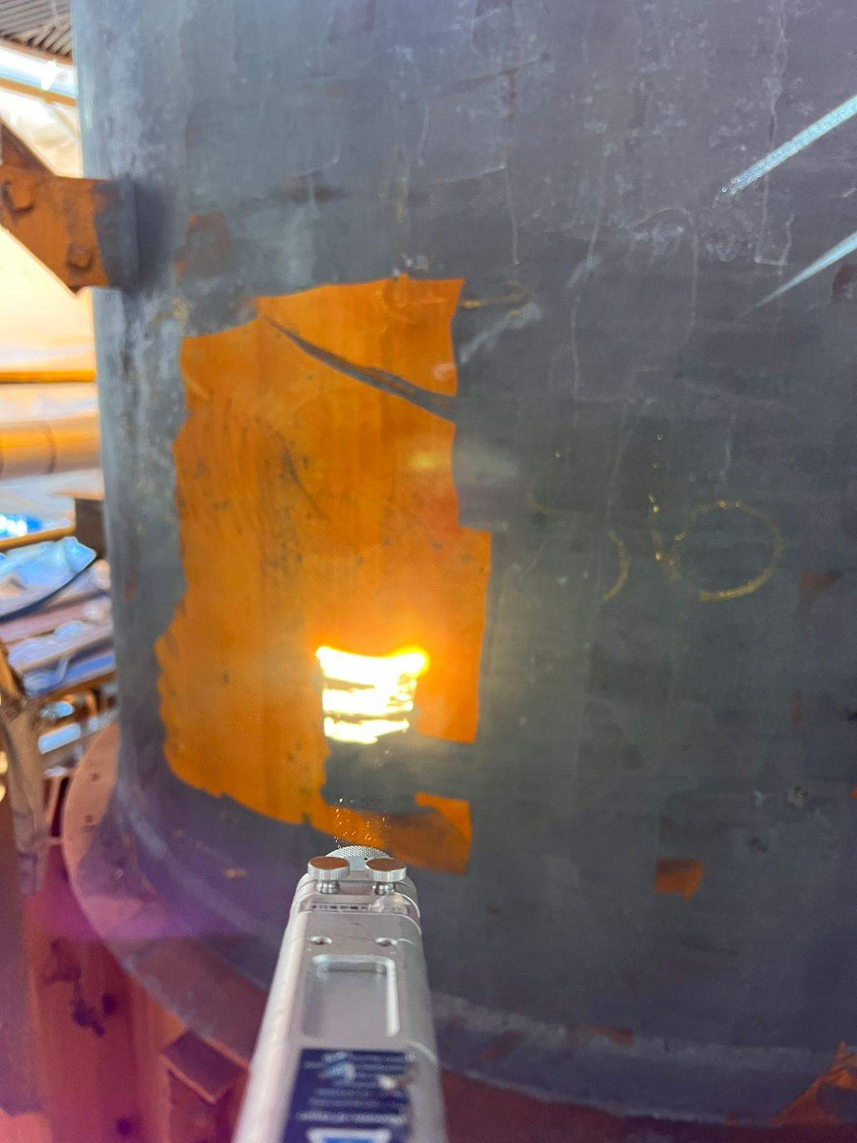 Laser cleaning head mid-pass, cleaned band visible behind it